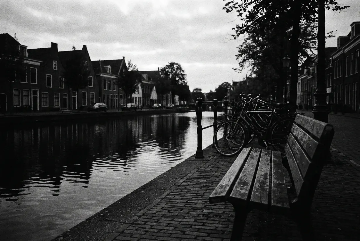 Leeg houten bankje langs een gracht in de schemering